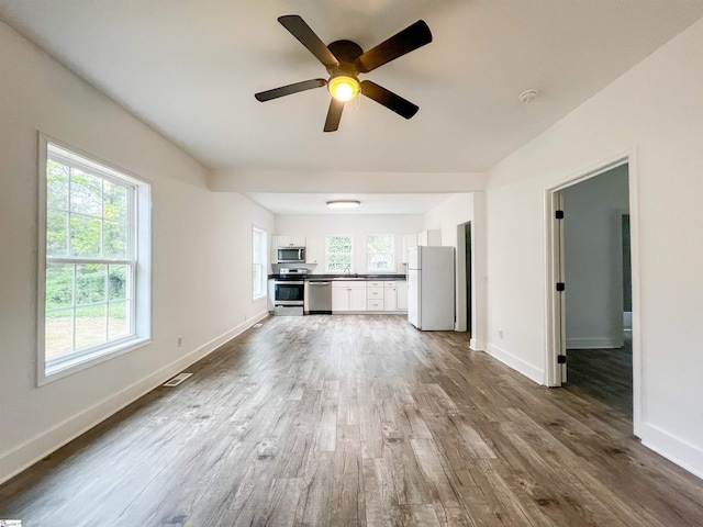 unfurnished living room featuring visible vents, baseboards, and dark wood-style floors