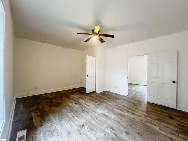 unfurnished bedroom with a ceiling fan, dark wood-type flooring, baseboards, and visible vents