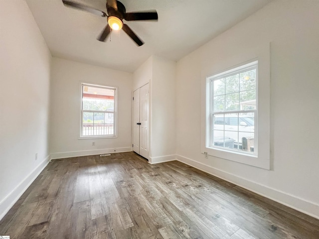 unfurnished bedroom with a ceiling fan, visible vents, wood finished floors, baseboards, and a closet