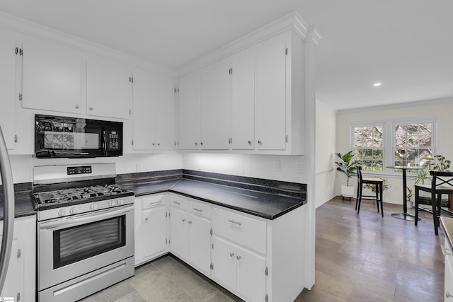 kitchen with dark countertops, stainless steel range with gas cooktop, black microwave, ornamental molding, and white cabinets