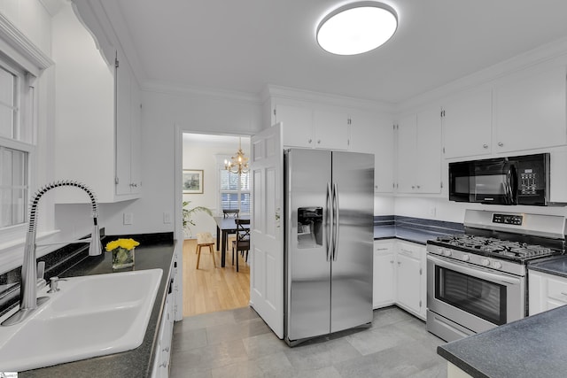 kitchen with a sink, stainless steel appliances, dark countertops, and white cabinetry