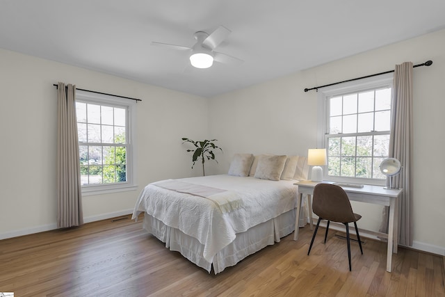 bedroom with multiple windows, baseboards, and wood finished floors