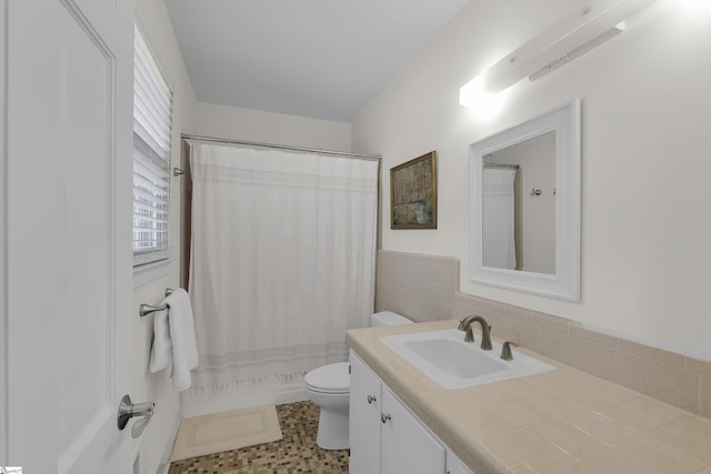 bathroom featuring vanity, tile walls, and toilet