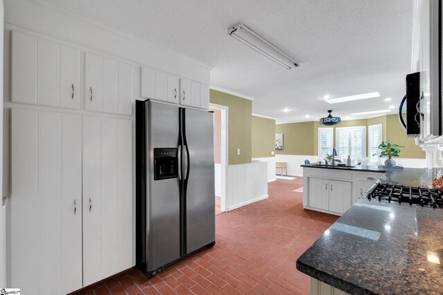 kitchen featuring dark countertops, a peninsula, brick floor, and stainless steel fridge with ice dispenser