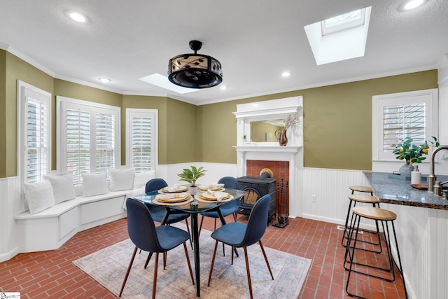 dining room featuring a wealth of natural light, a wainscoted wall, a skylight, and brick floor