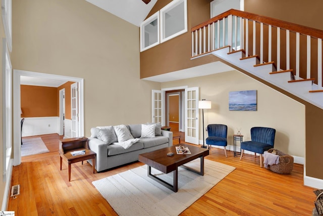 living area featuring french doors, visible vents, wood finished floors, and stairs