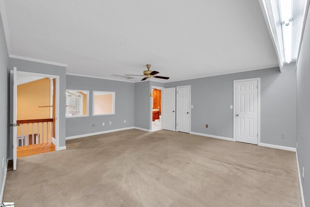 interior space featuring ceiling fan, ornamental molding, baseboards, and light carpet