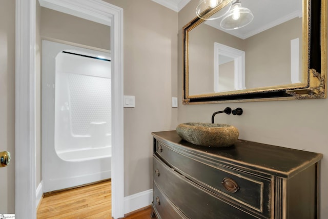 bathroom with vanity, crown molding, wood finished floors, and baseboards