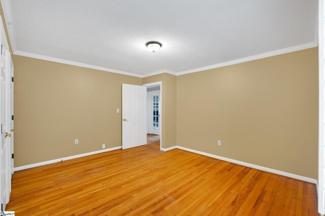 unfurnished room featuring baseboards, light wood-style floors, crown molding, and a textured ceiling