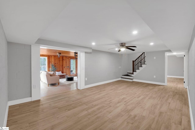 unfurnished living room with stairway, a ceiling fan, baseboards, recessed lighting, and light wood-style floors