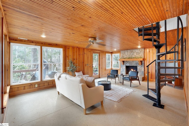 living area with stairway, wooden ceiling, a fireplace, and wooden walls