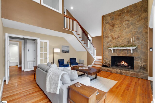 living area with stairway, wood finished floors, baseboards, a high ceiling, and a fireplace