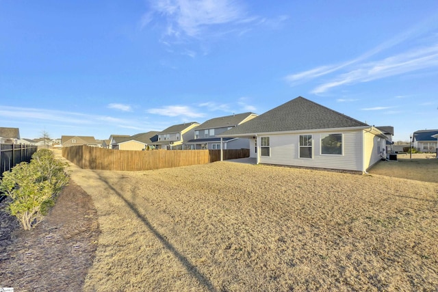 back of property featuring a residential view, a shingled roof, and fence