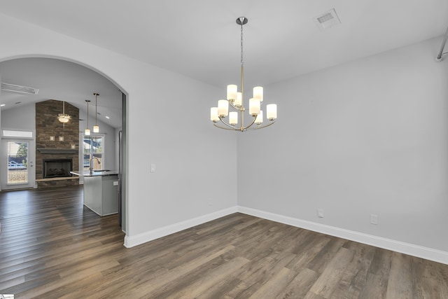 unfurnished dining area with visible vents, a large fireplace, and dark wood-type flooring