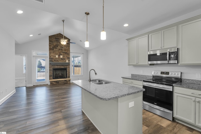 kitchen featuring a sink, light stone counters, open floor plan, appliances with stainless steel finishes, and a fireplace