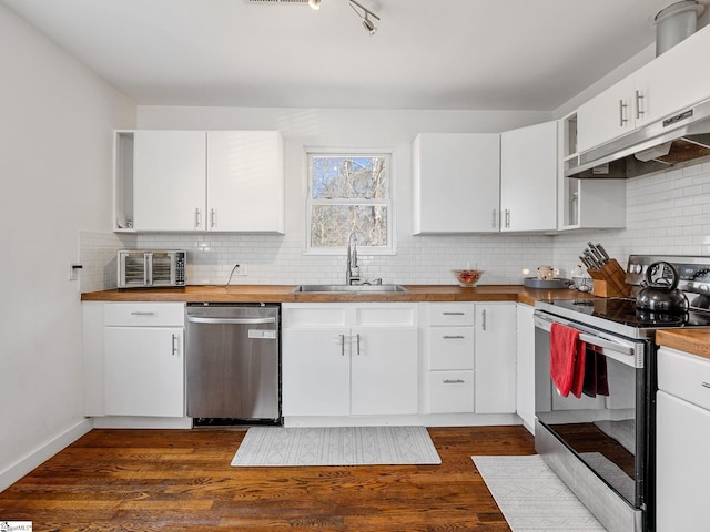 kitchen featuring butcher block countertops, a sink, dark wood-type flooring, appliances with stainless steel finishes, and backsplash