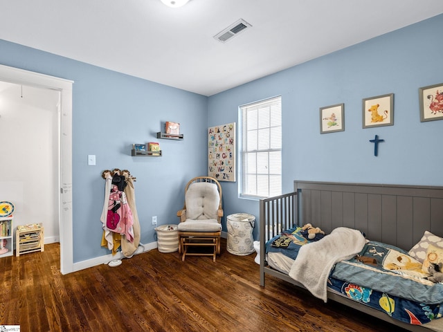 bedroom featuring visible vents, baseboards, and wood finished floors