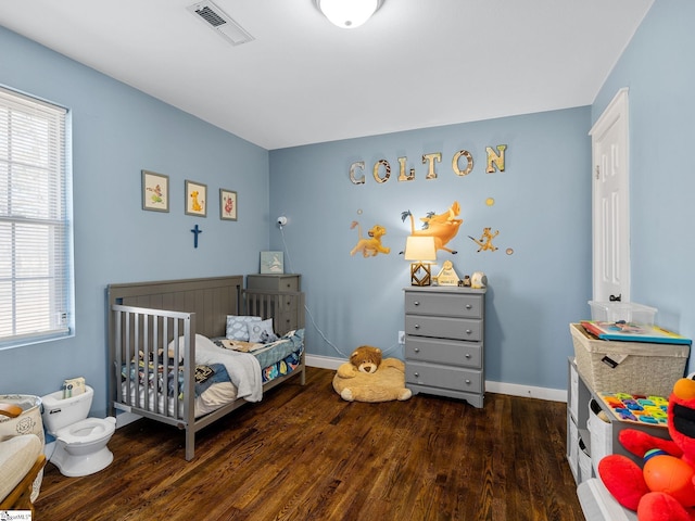 bedroom with visible vents, baseboards, and wood finished floors