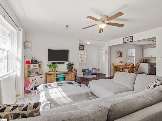 living area featuring visible vents, baseboards, ceiling fan, and wood finished floors