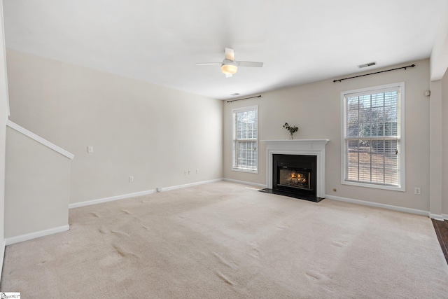 unfurnished living room featuring visible vents, baseboards, carpet, and a fireplace with flush hearth