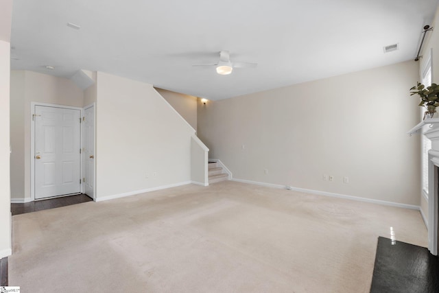 unfurnished living room featuring visible vents, stairway, carpet flooring, a fireplace, and a ceiling fan