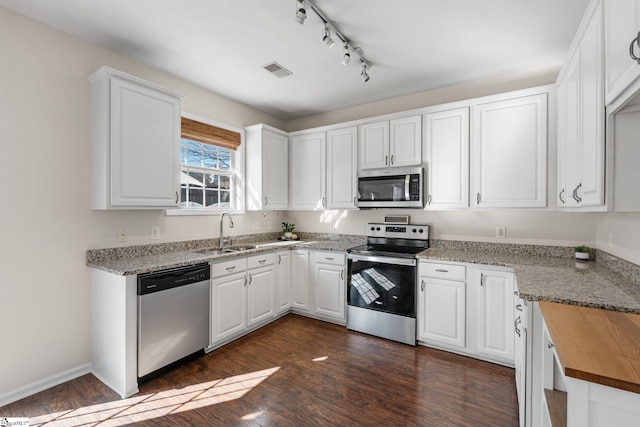 kitchen featuring visible vents, dark wood-style flooring, a sink, white cabinets, and appliances with stainless steel finishes