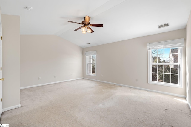 spare room with vaulted ceiling, a healthy amount of sunlight, visible vents, and light carpet