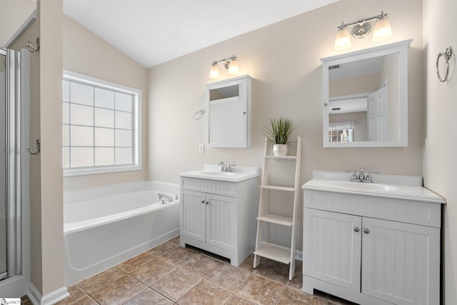 bathroom with two vanities, lofted ceiling, a garden tub, and a sink