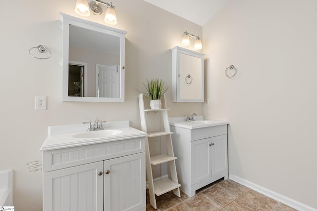 bathroom featuring tile patterned flooring, two vanities, baseboards, and a sink