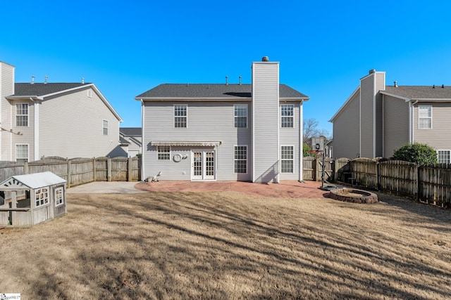 back of property with a yard, a patio area, a fenced backyard, and an outdoor fire pit