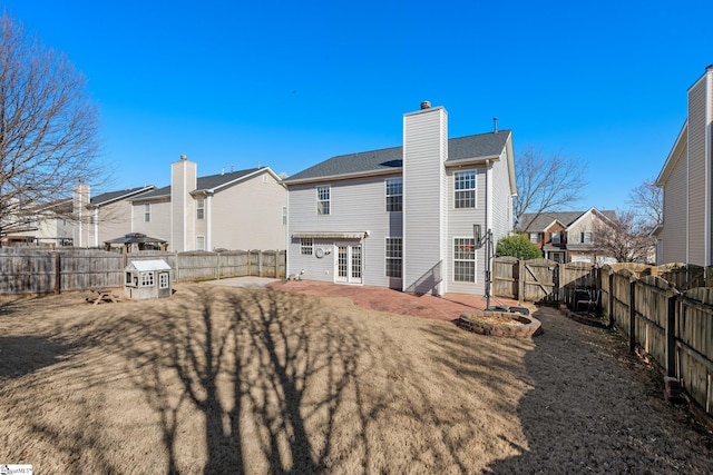 rear view of house featuring a residential view, a fenced backyard, a chimney, and a patio area