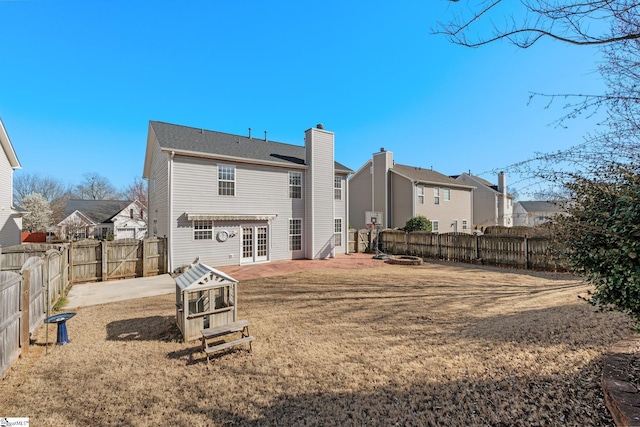 rear view of house with a patio, a fenced backyard, french doors, a fire pit, and a chimney