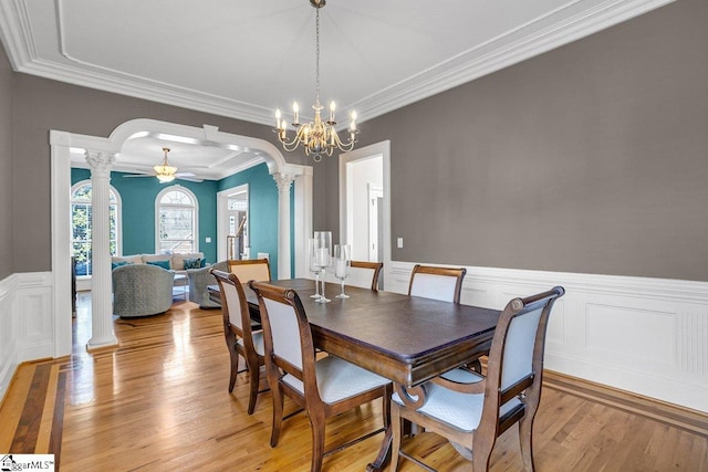 dining space with arched walkways, ornamental molding, light wood-type flooring, and decorative columns