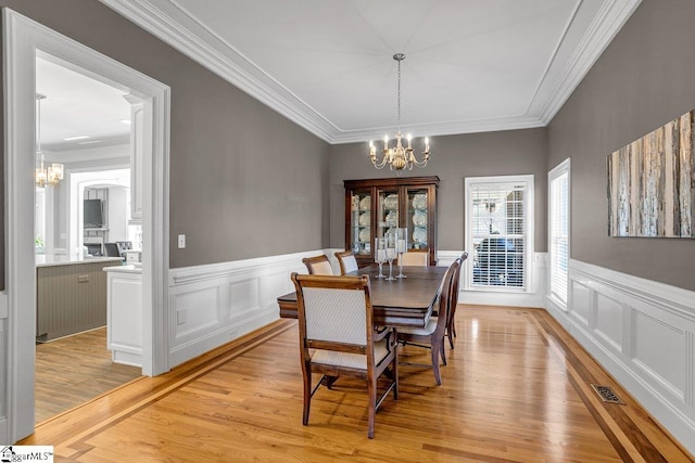 dining room featuring visible vents, light wood-style floors, an inviting chandelier, and ornamental molding