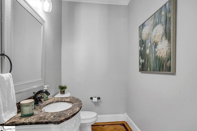 bathroom with baseboards, toilet, and vanity