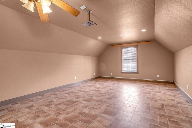 additional living space with ceiling fan, a textured ceiling, baseboards, and vaulted ceiling