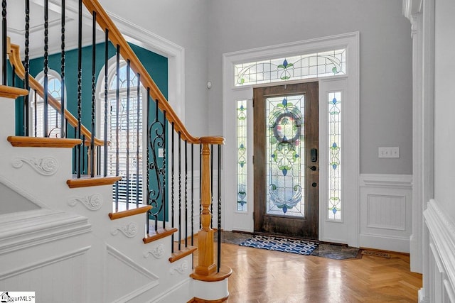 foyer entrance featuring stairway, a wainscoted wall, and a decorative wall