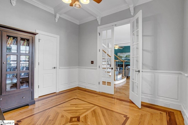 unfurnished room featuring crown molding, beam ceiling, french doors, a decorative wall, and a ceiling fan