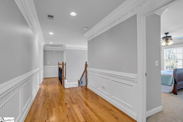 hallway with visible vents, light wood-type flooring, ornamental molding, an upstairs landing, and recessed lighting