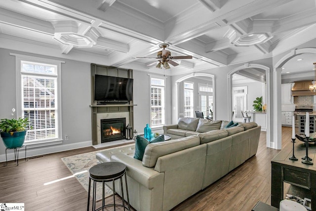 living room with wood finished floors, beamed ceiling, a fireplace, and coffered ceiling