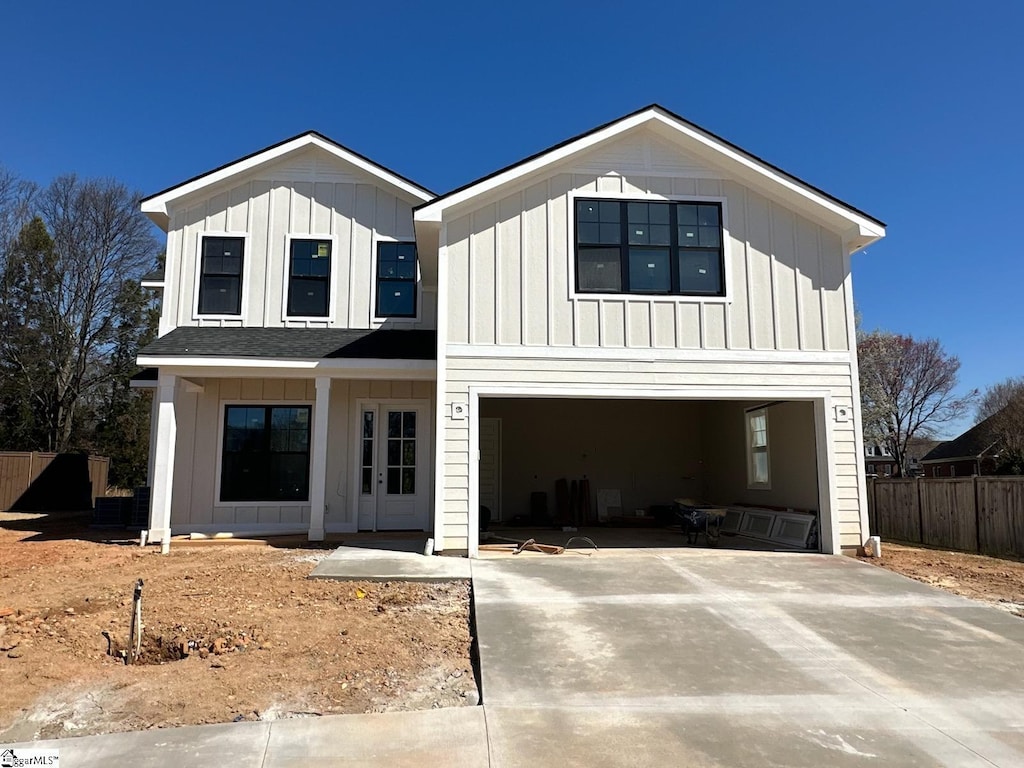 modern inspired farmhouse with board and batten siding, an attached garage, driveway, and fence