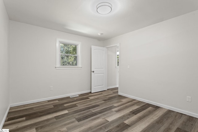 spare room featuring visible vents, baseboards, and wood finished floors