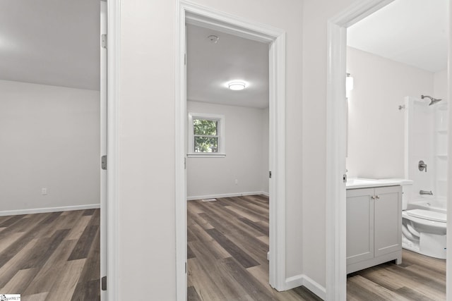 bathroom with baseboards, toilet, bathing tub / shower combination, wood finished floors, and vanity