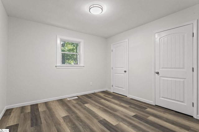 unfurnished bedroom featuring baseboards, visible vents, and dark wood-style flooring