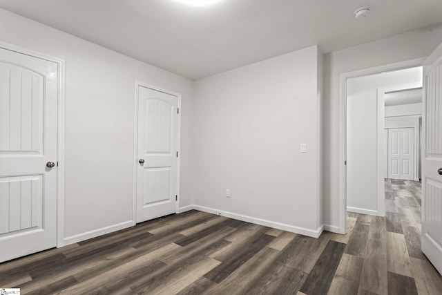 unfurnished bedroom with dark wood-type flooring and baseboards