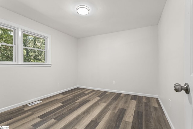 unfurnished room featuring visible vents, baseboards, and dark wood-style floors