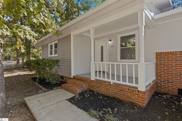 entrance to property with crawl space, covered porch, and brick siding