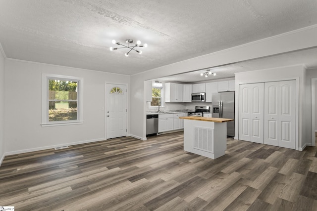 kitchen featuring dark wood-style floors, stainless steel appliances, white cabinets, crown molding, and butcher block counters