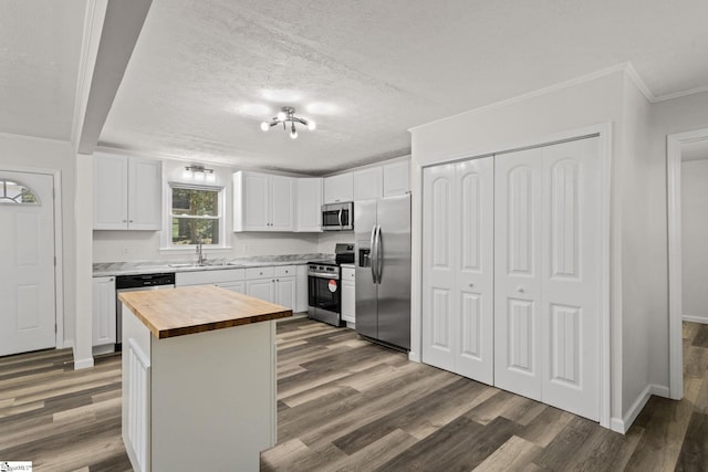 kitchen with crown molding, stainless steel appliances, white cabinetry, wood counters, and dark wood-style flooring