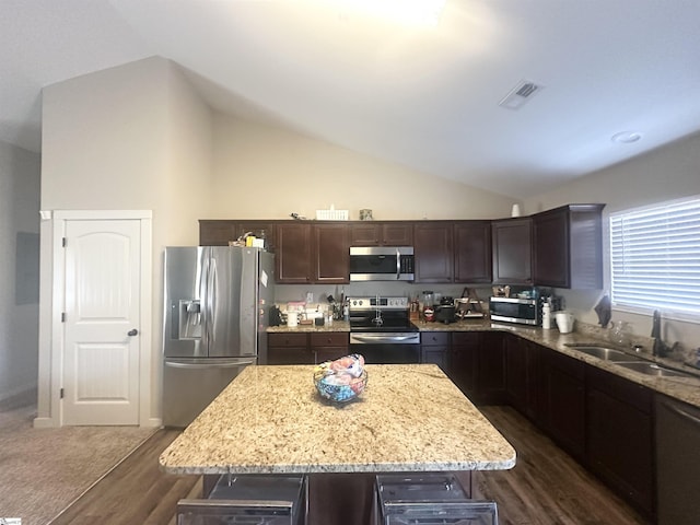 kitchen featuring visible vents, a sink, light stone counters, dark brown cabinetry, and appliances with stainless steel finishes